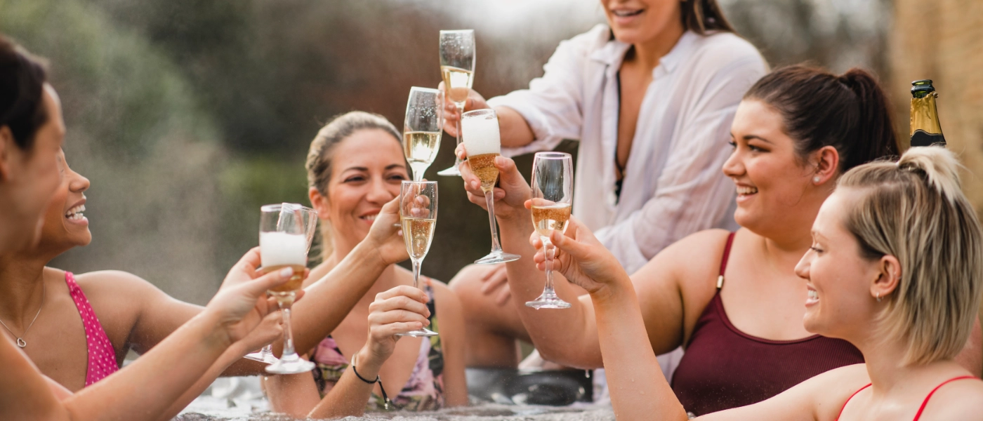 A group of friends with champagne glasses in a hot tub.