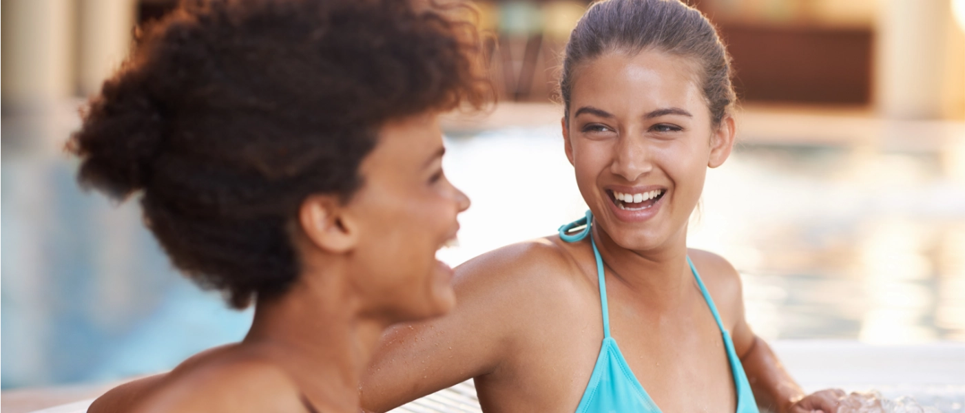 two women sitting in a hot tub, smiling.